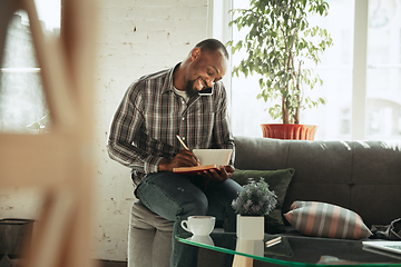 Image showing African-american man, freelancer during the work in home office while quarantine