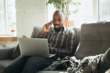 Image showing African-american man, freelancer during the work in home office while quarantine