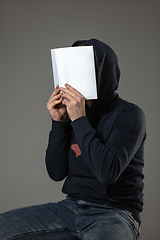 Image showing Happy world book day, read to become someone else - man covering face with book while reading on grey background