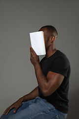 Image showing Happy world book day, read to become someone else - man covering face with book while reading on grey background