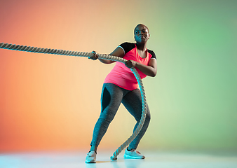 Image showing Young african-american plus size female model\'s training on gradient background