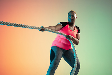 Image showing Young african-american plus size female model\'s training on gradient background