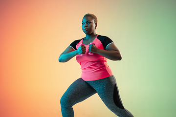 Image showing Young african-american plus size female model\'s training on gradient background