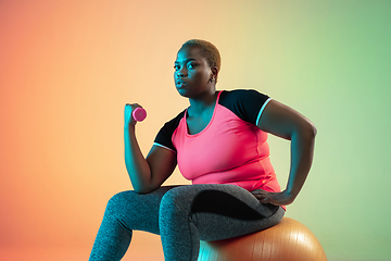 Image showing Young african-american plus size female model\'s training on gradient background