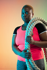 Image showing Young african-american plus size female model\'s training on gradient background