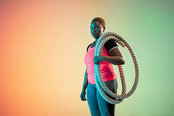 Image showing Young african-american plus size female model\'s training on gradient background