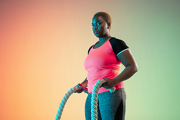 Image showing Young african-american plus size female model\'s training on gradient background