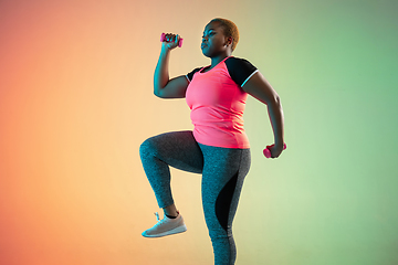 Image showing Young african-american plus size female model\'s training on gradient background