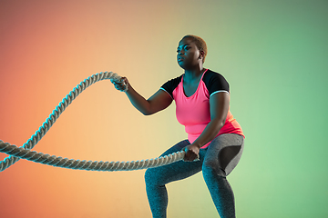 Image showing Young african-american plus size female model\'s training on gradient background