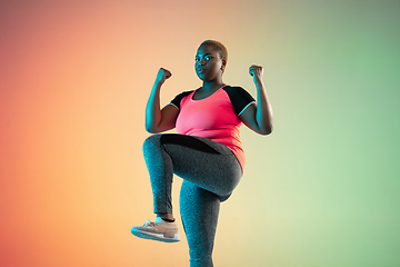 Image showing Young african-american plus size female model\'s training on gradient background