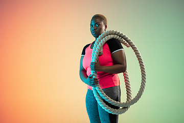 Image showing Young african-american plus size female model\'s training on gradient background