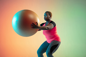 Image showing Young african-american plus size female model\'s training on gradient background