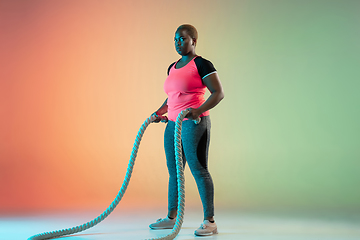 Image showing Young african-american plus size female model\'s training on gradient background