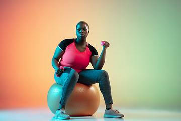 Image showing Young african-american plus size female model\'s training on gradient background