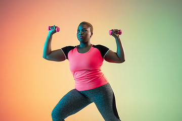 Image showing Young african-american plus size female model\'s training on gradient background