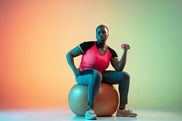 Image showing Young african-american plus size female model\'s training on gradient background