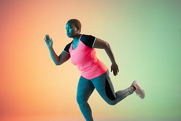 Image showing Young african-american plus size female model\'s training on gradient background