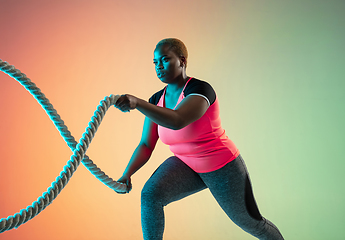 Image showing Young african-american plus size female model\'s training on gradient background