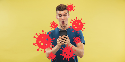 Image showing Young man using phone, watching news of coronavirus spreading and worldwide cases, shocked and sad