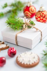 Image showing Christmas composition. Christmas gift, fir branches on wooden white background with gingerbread cookie