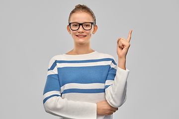 Image showing happy teenage girl in glasses pointing finger up