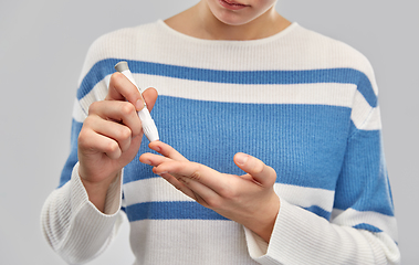 Image showing teenage girl making blood test with lancing device