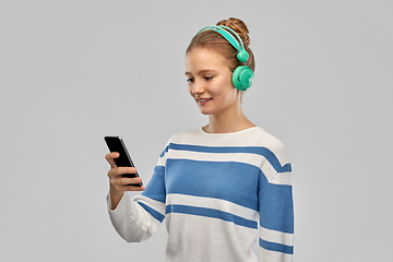 Image showing smiling teenage girl in headphones with smartphone