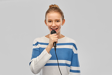 Image showing smiling teenage girl with microphone singing