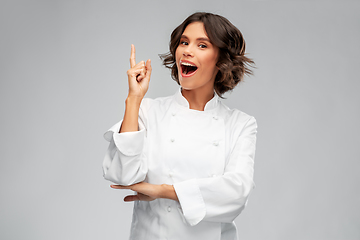 Image showing smiling female chef in toque pointing finger up