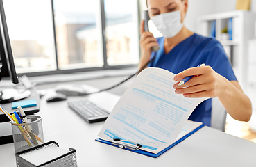 Image showing doctor with computer calling on phone at hospital