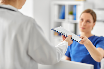 Image showing nurse giving clipboard to doctor at hospital