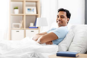 Image showing happy smiling indian man lying in bed at home