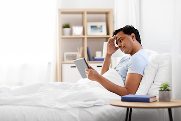 Image showing stressed indian man with tablet pc in bed at home