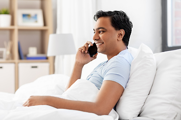 Image showing happy indian man calling on smartphone in bed