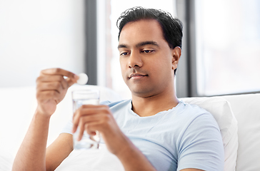 Image showing man in bed dropping medicine into glass of water