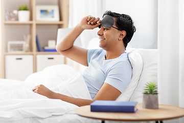 Image showing happy smiling indian man lying in bed at home