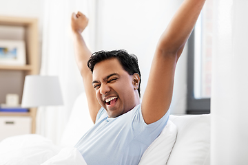 Image showing happy smiling indian man lying in bed at home