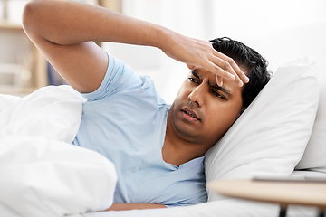 Image showing indian man having headache lying in bed at home