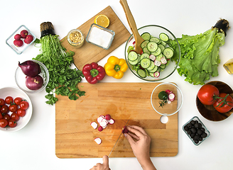 Image showing hands chopping radish for salad at kitchen