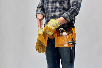 Image showing builder with working tools putting gloves on