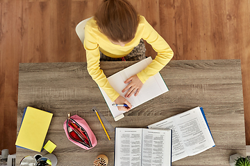 Image showing student girl with book writing to notebook at home