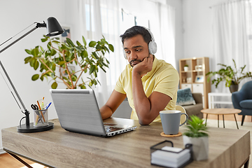 Image showing man in headphones with laptop working at home