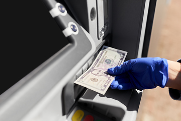 Image showing hand in medical glove with money at atm machine