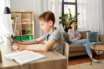 Image showing mother with smartphone and son learning at home