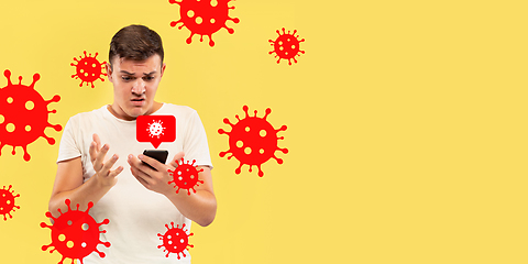 Image showing Young man using phone, watching news of coronavirus spreading and worldwide cases, shocked and sad
