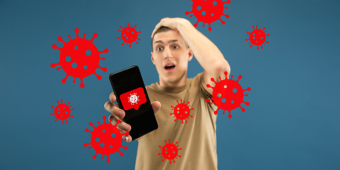 Image showing Young man using phone, watching news of coronavirus spreading and worldwide cases, shocked and sad