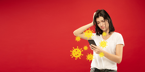 Image showing Young woman using phone, watching news of coronavirus spreading and worldwide cases, shocked and sad