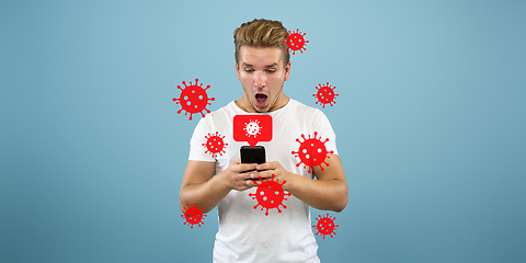 Image showing Young man using phone, watching news of coronavirus spreading and worldwide cases, shocked and sad