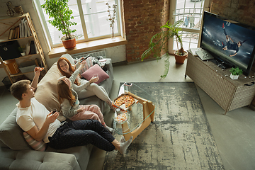 Image showing Family spending nice time together at home, looks happy and excited, eating pizza, watching female football match