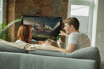 Image showing Family spending nice time together at home, looks happy and excited, eating pizza, watching rugby match